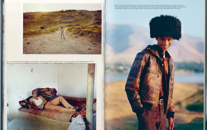 Fashion editorial photograph featuring a smiling man wearing a brown jacket and furry hat, with a desert landscape and river in the background.