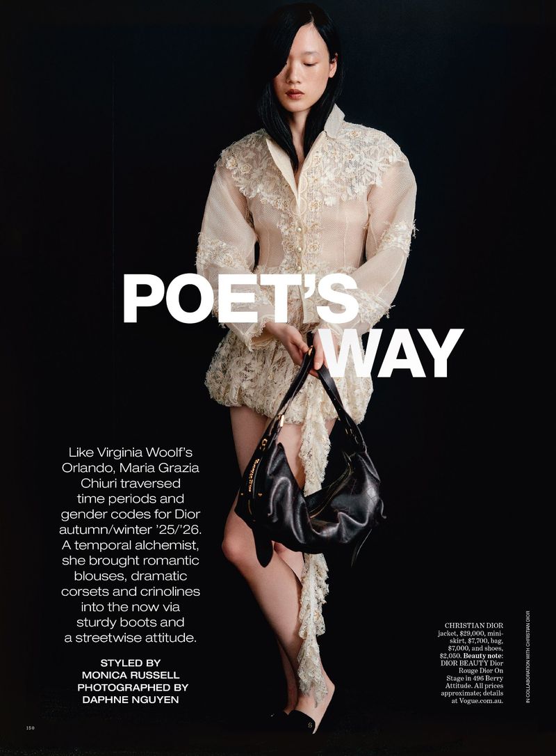 Editorial fashion shot: Young Asian woman poses in a lace-trimmed dress, holding a black purse against a dark backdrop. Fashion magazine.