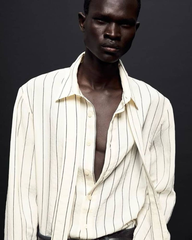 Model wearing a white and black striped long-sleeve shirt against a dark grey background for Zara Man Oct 2024 Lookbook
