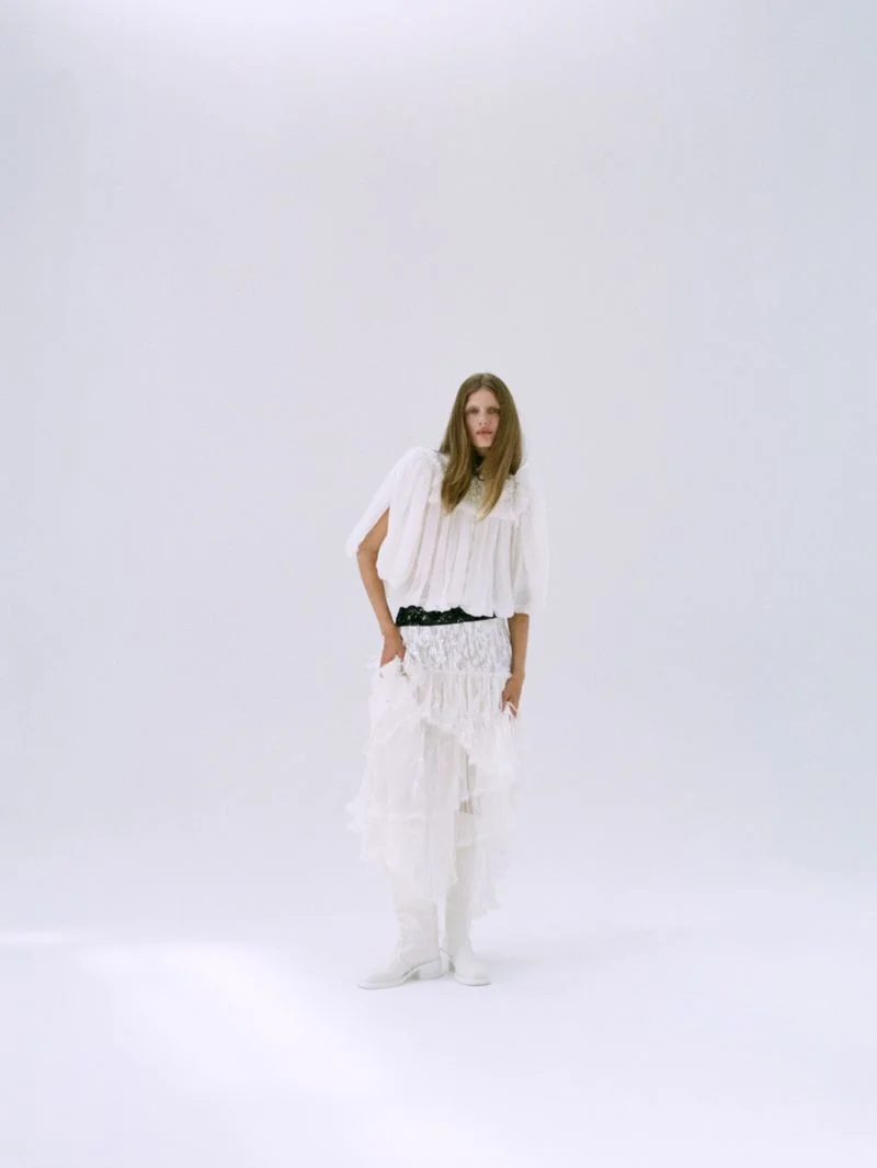Model Rosalieke Fuchs wearing white top and ruffled skirt against a plain white studio background