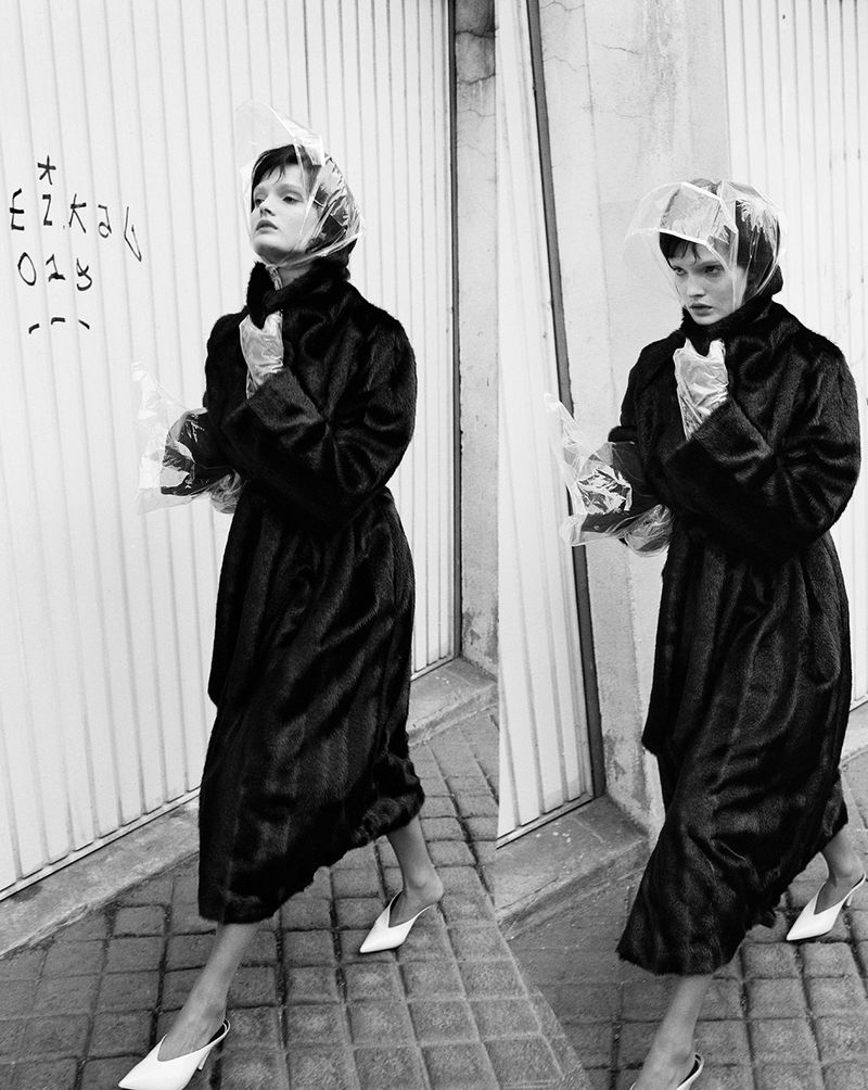 Monochrome street style: Woman in dark coat and plastic head covering walks on tiled sidewalk, by graffiti wall, captured in a diptych.