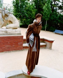 Model Lulu Tenney in a long brown textured coat standing outdoors near a stone sculpture for D Repubblica