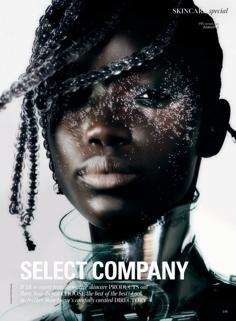 Close-up portrait of a dark-skinned woman with silver braids and shimmering makeup against a bright backdrop, emphasizing beauty and skincare.