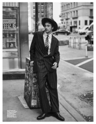 Man wearing a pinstripe suit and fedora hat posing on a city street for an Esquire US fashion editorial.