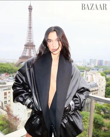 Fashion shot of a woman in a dark coat with Paris' Eiffel Tower in the background, shot for Bazaar fashion magazine publication.