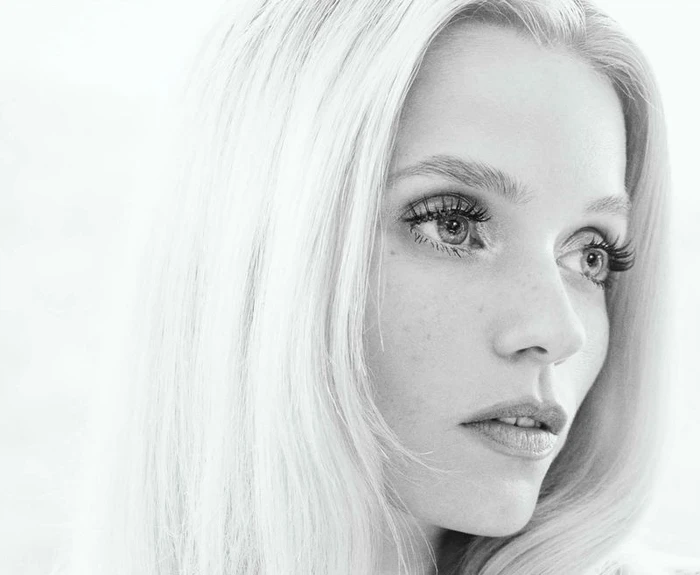 Close-up black and white portrait of model Abbey Lee with blonde hair and defined eyelashes against a light background