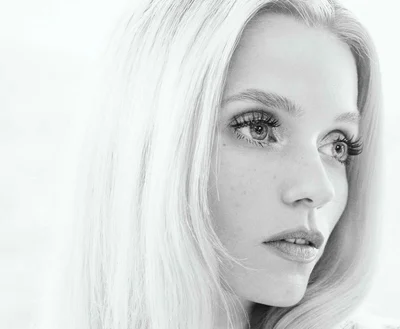 Close-up black and white portrait of model Abbey Lee with blonde hair and defined eyelashes against a light background