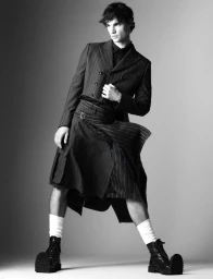 Male model Fernando Lindez wearing a pinstripe jacket and utility kilt with boots in a monochrome fashion editorial for V Man.