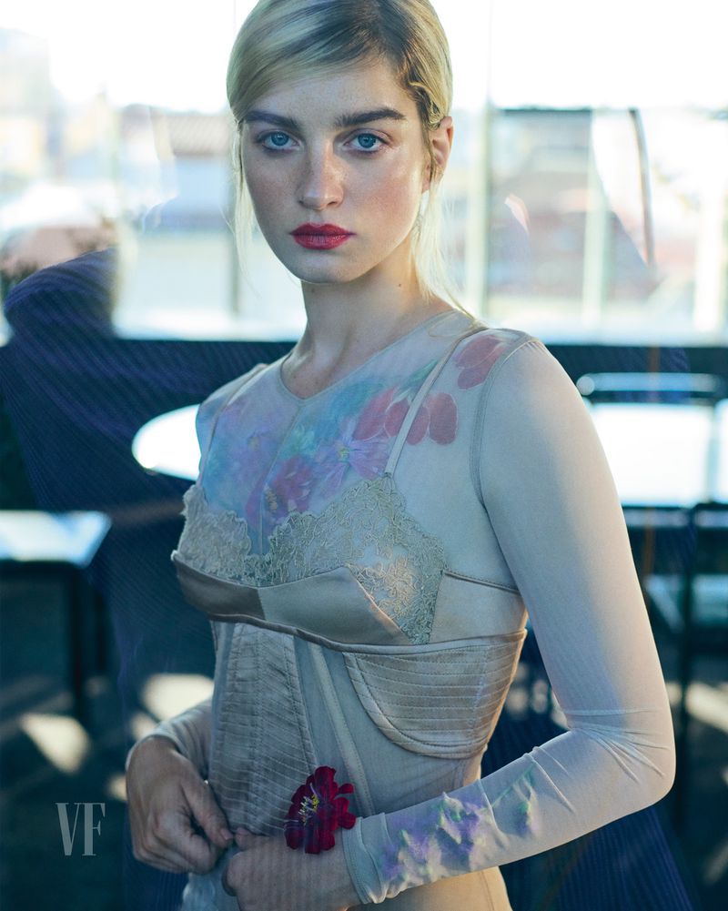 Model Adèle Farine wearing a sheer floral printed long-sleeve top and satin corset looking directly into the camera.