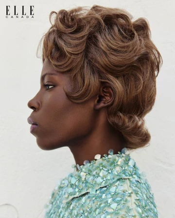 Profile portrait of an adult woman with brown wavy hair wearing a light blue beaded top, captured in a beauty fashion editorial style.