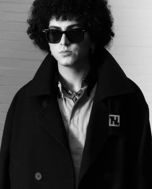 Monochrome portrait of a model with dark curly hair wearing sunglasses and a heavy coat for Esquire Italia