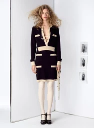 Apolline Rocco Fohrer in a black and cream knit dress with white tights and black platform heels against a white studio flat corner.