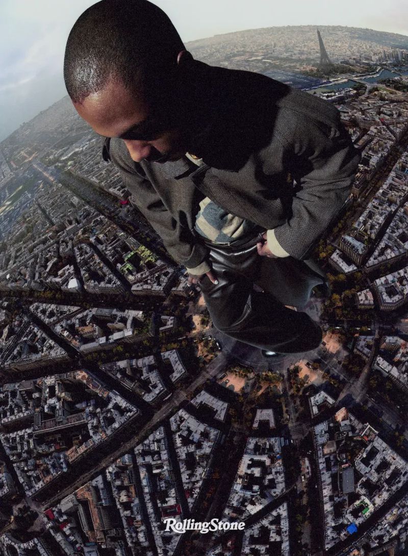 Aerial shot featuring an African American man in dark coat over a cityscape, highlighting architectural details and an urban landscape.