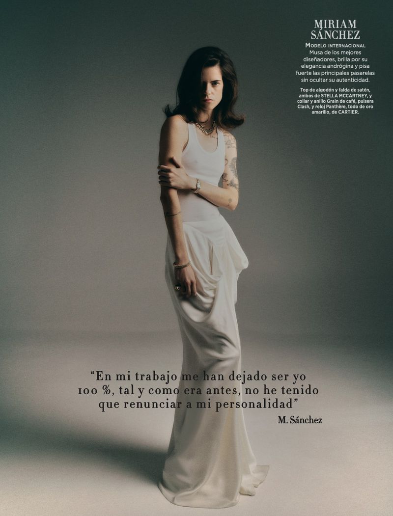 Fashion editorial shot of a brunette woman in a white dress posing in a photo studio with soft lighting, neutral background and jewelry.