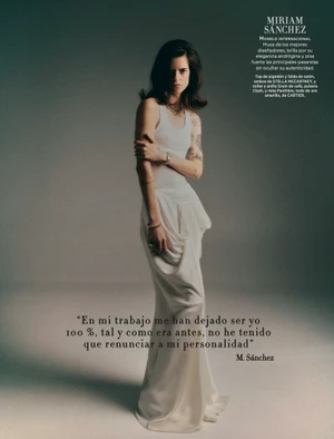 Model Miriam Sanchez standing in a white tank top and draped ivory satin maxi skirt against a neutral studio backdrop.