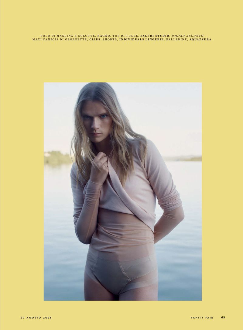 Young woman in lingerie and a long-sleeved shirt poses in front of a body of water, outdoors on a sunny day. Fashion editorial.