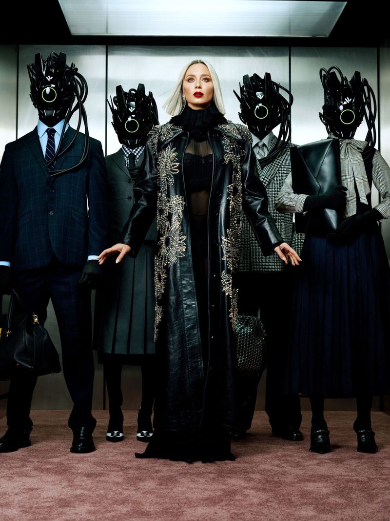Stylish woman in a black coat surrounded by figures in suits and masks in an elevator, creating a surreal, high-fashion, editorial image.