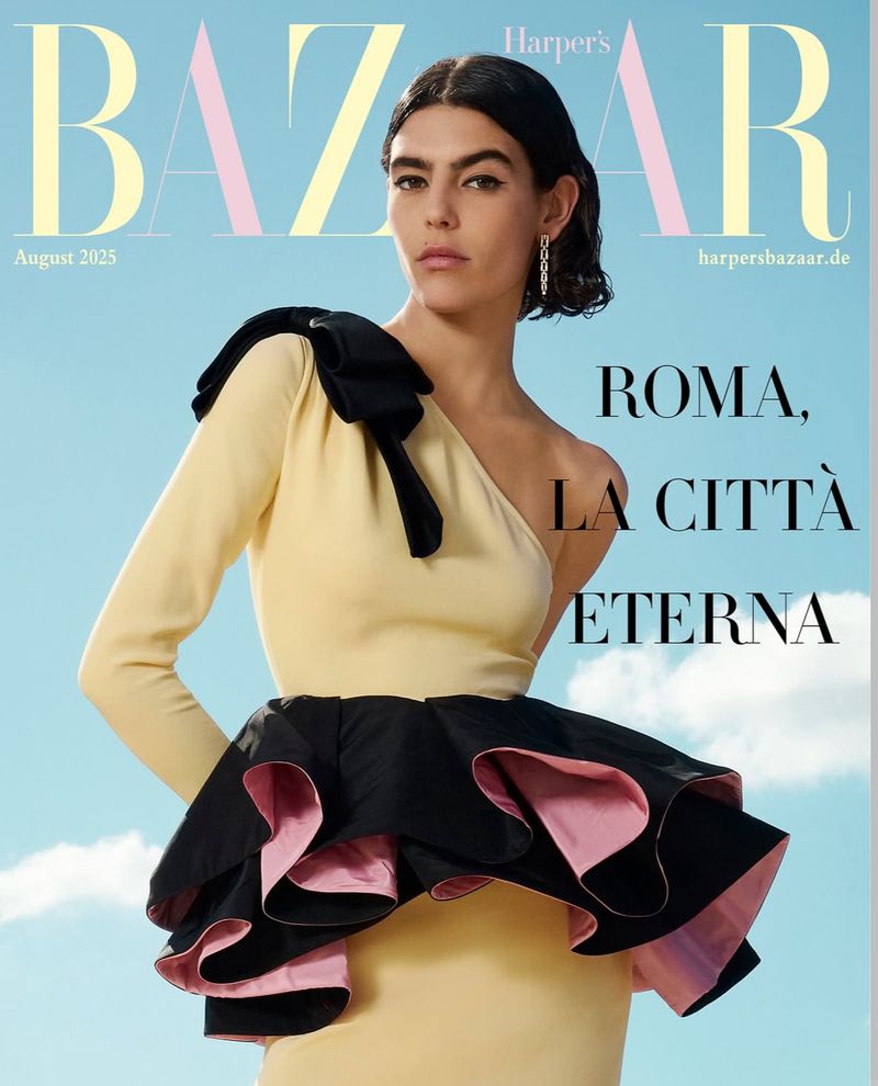 Harper's Bazaar August 2025 cover features a woman in a one-shoulder yellow dress with black bow and ruffle, posing against a blue sky.