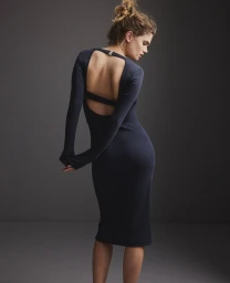 Model in a dark navy long-sleeve backless midi dress standing against a plain grey studio backdrop for Replay FW24.