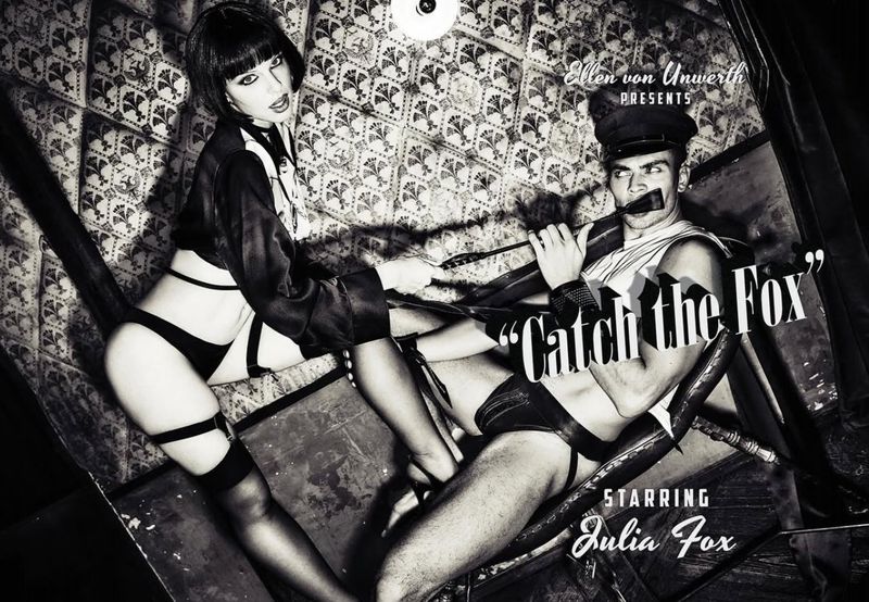 Black and white fashion shot of a woman with a bob haircut holding a riding crop with a man in a hat holding a rifle.