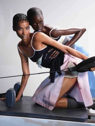 Two fashion models posing together on a pilates reformer machine in an editorial studio shoot for FAZ Magazine.