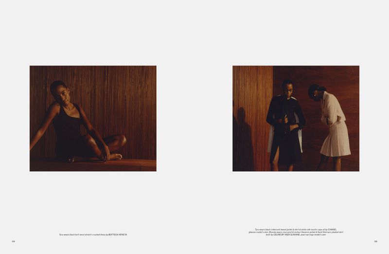 Editorial fashion shot: one woman in black dress sitting in front of wood panels, with two women in background wearing fashionable clothes.