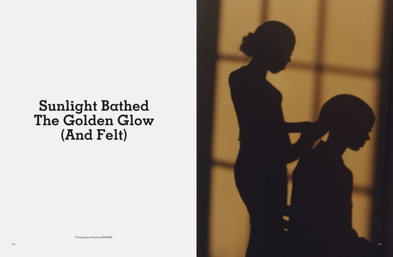 Silhouette of two figures in a warm, golden light, one attending to the other's hair near a window casting soft shadows.