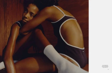 Two models wearing dark swimwear and white socks pose indoors against dark wood paneling for Pop Magazine