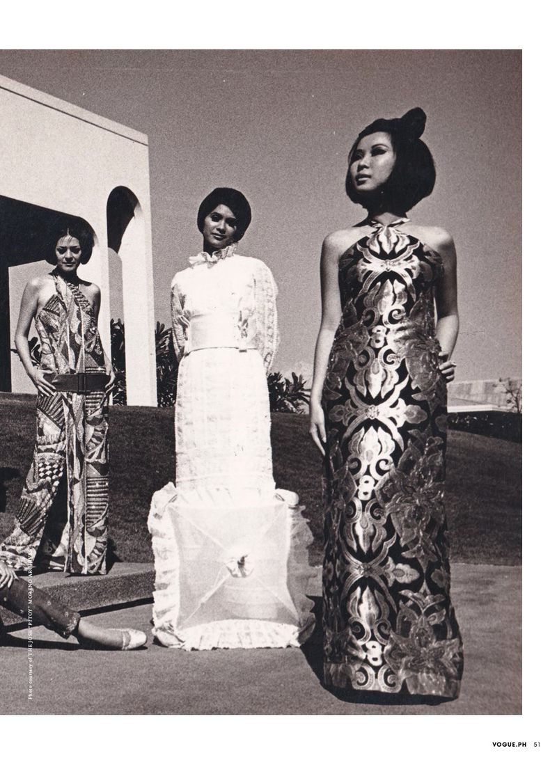 Three women in elegant dresses pose outdoors against a neutral building. They are shown in a vintage fashion editorial style.