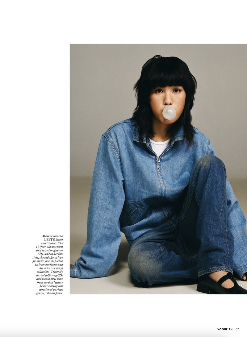 Woman in denim jacket and jeans poses indoors blowing a bubble. Fashion editorial with casual style, natural light, and youthful vibe.