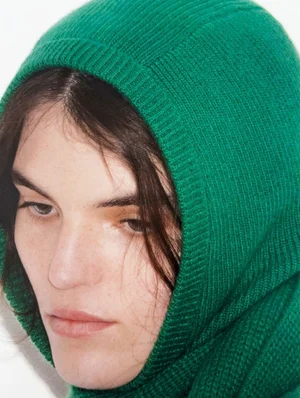 Close-up portrait of a model wearing a bright green ribbed knit hood for the RE/DONE Winter 2024 lookbook.