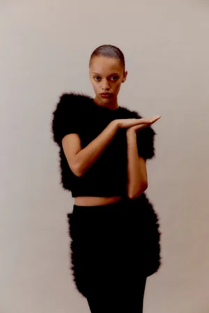 Model Kukua Williams wearing a textured black fuzzy top against a neutral studio backdrop for Blanc Magazine.