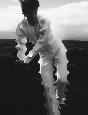Model Maaike Klaasen wearing a structured white outfit posing outdoors against a rocky terrain for Numero Switzerland.
