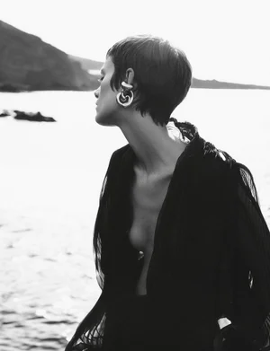 Model Maaike Klaasen in a black top with large silver earrings outdoors near water for Numero Switzerland