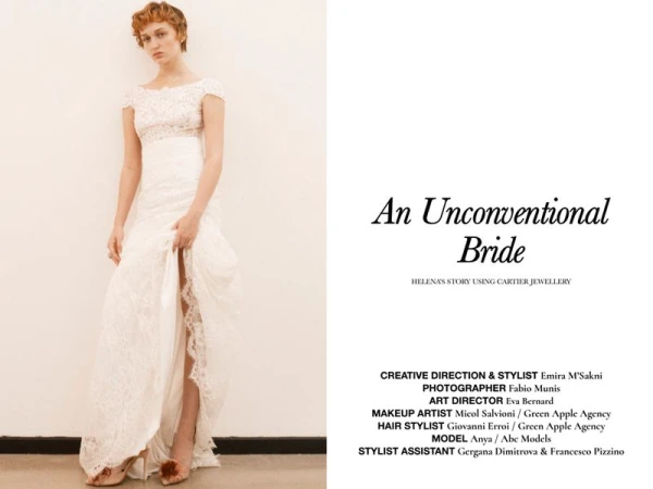 Model with short red hair wearing a white lace wedding dress against a plain neutral background in an editorial shot