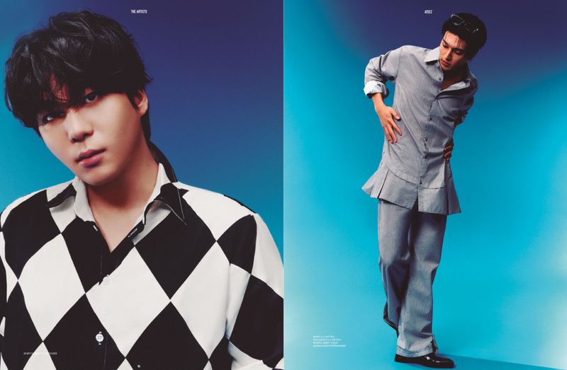 Two young Asian men pose indoors against a blue backdrop, one wearing a black and white diamond-patterned shirt, the other in a grey striped suit.