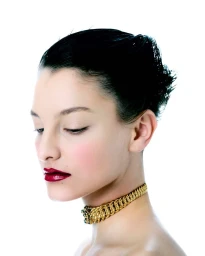 Close-up portrait of a woman wearing a gold choker necklace and dark red lipstick against a plain white background.