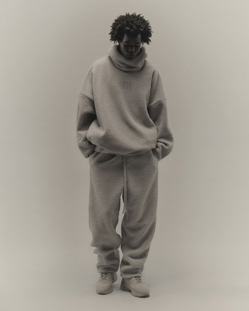 Full-length portrait of an African American adult male in a soft grey fuzzy sweater and sweatpants, posing in front of a neutral backdrop.