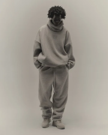 Full-length portrait of an African American adult male in a soft grey fuzzy sweater and sweatpants, posing in front of a neutral backdrop.