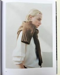 Mollie Cotter in profile wearing a white top with a brown knit sweater draped over her shoulders against a pale studio backdrop.