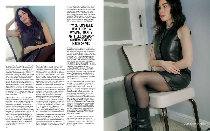 Woman with dark hair in a black dress seated on a chair in a photo studio, looking at the camera. Editorial fashion shot.