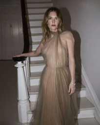Meghann Fahy standing on a staircase wearing a sheer neutral tulle gown for Marie Claire Australia