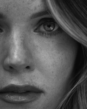 Monochrome extreme close-up portrait of Meghann Fahy showing natural freckled skin texture and direct gaze.
