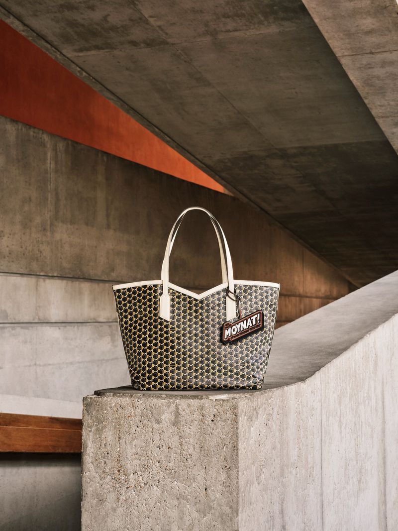 Moynat Paris tote bag on a concrete block, angular concrete structure in the background, underpass with orange detail.