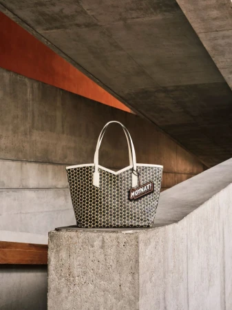 Moynat Paris tote bag on a concrete block, angular concrete structure in the background, underpass with orange detail.