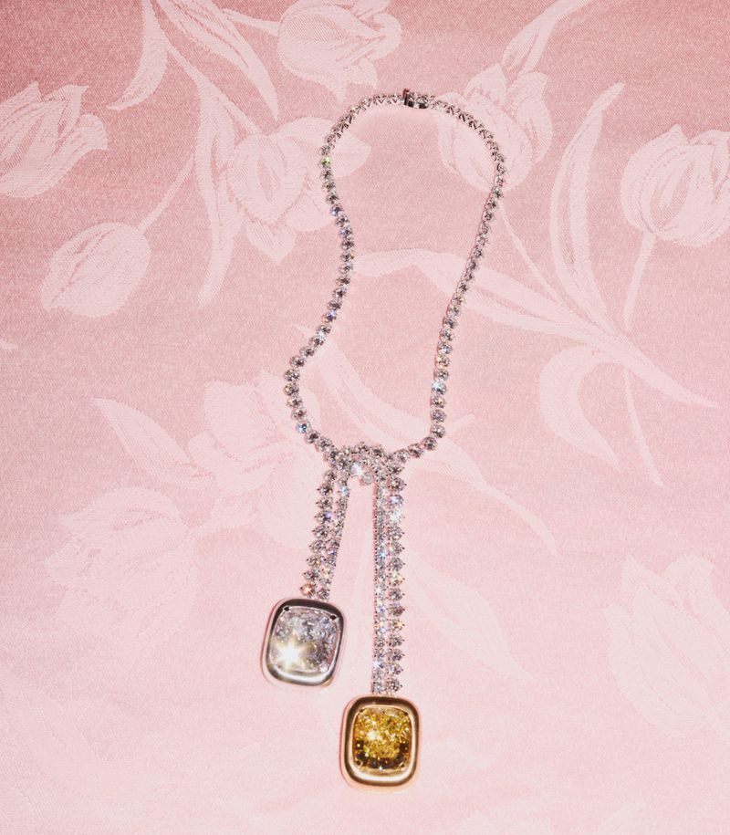 Elegant diamond necklace featuring yellow and white pendants on a pink floral background. A luxury jewelry item for fashion and beauty.