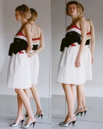 Model Vakare Steputyte wearing a layered white skirt and dark top reflected in a mirror for SSAW Magazine.
