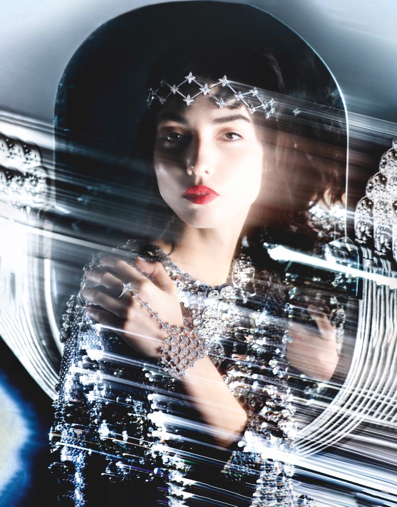 Elegant woman in a sequined dress and hat, adorned with jewelry, strikes a pose. Bright, blurred light streaks add a dynamic feel.