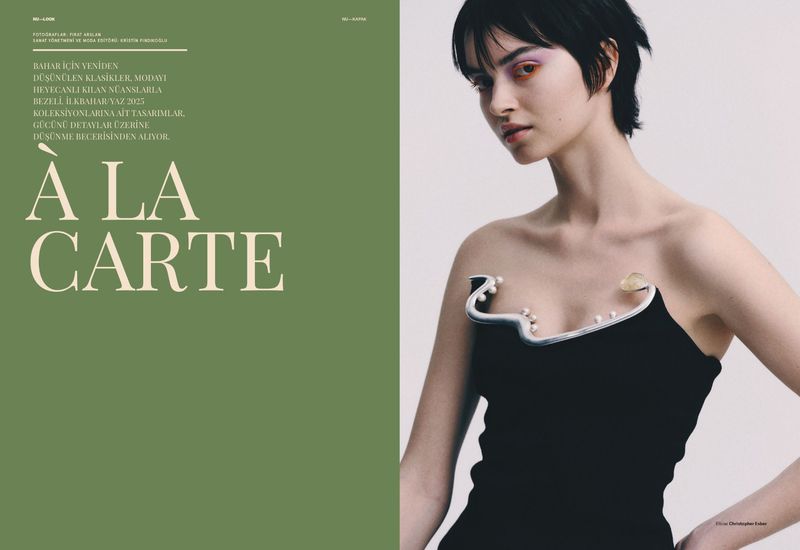 A young woman poses in a black strapless dress with unique pearl and silver trim, captured in a fashion editorial against a clean backdrop.