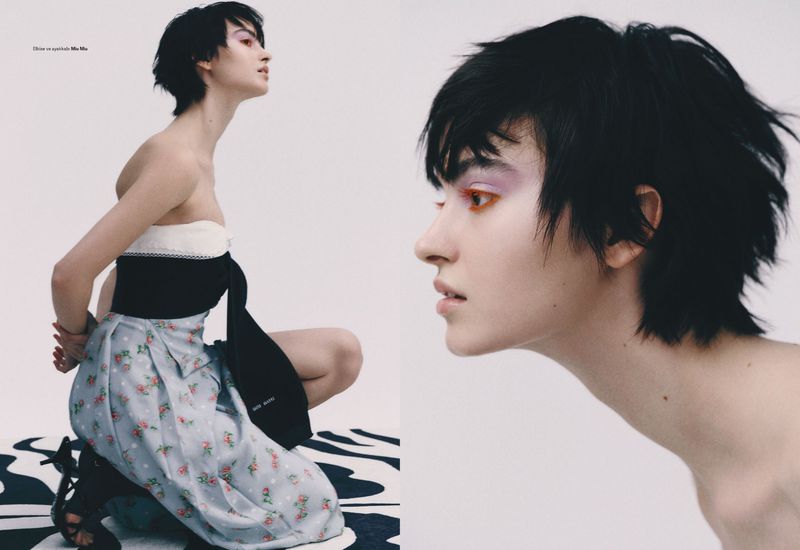 Fashion editorial image featuring an adult female model with short dark hair, makeup, and a floral dress posing in a photo studio.